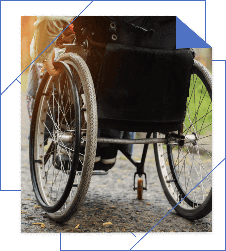 Close-up view of a wheelchair on an outdoor path, showing its wheels and part of the seat. Sunlight filters through the background.